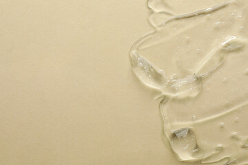 Clear cosmetic gel on beige background, top view. Space for text