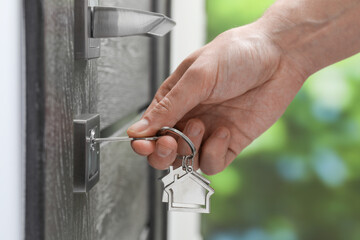 Man unlocking door with key outdoors, closeup