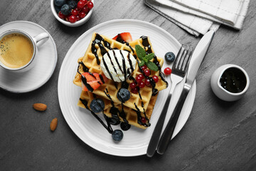 Delicious Belgian waffles with ice cream, berries and chocolate sauce served on grey textured...