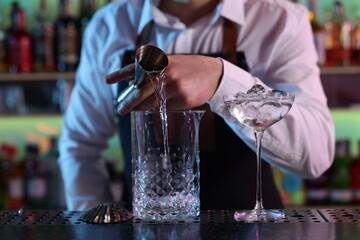 Bartender making fresh alcoholic cocktail at counter in bar, closeup