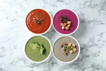 Different tasty cream soups in bowls on white marble table, flat lay