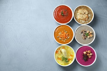 Tasty broth and different cream soups in bowls on gray table, flat lay. Space for text