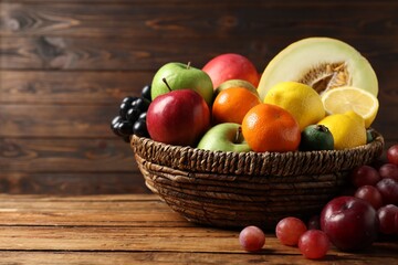 Different ripe fruits in wicker basket on wooden table, closeup. Space for text
