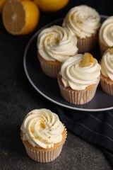 Delicious cupcakes with white cream and lemon zest on table