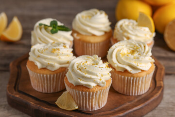 Delicious cupcakes with white cream and lemon zest on wooden table, closeup