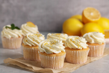 Delicious cupcakes with white cream and lemon zest on table, closeup