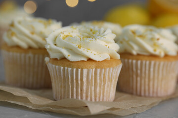 Delicious cupcakes with white cream and lemon zest on table, closeup