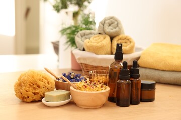 Dry flowers, loofah, soap bar, bottles of essential oils and jar with cream on wooden table...