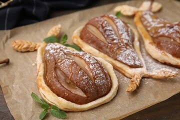 Delicious pears baked in puff pastry with powdered sugar and mint on table, closeup