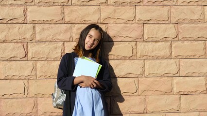 Portrait of a funny schoolgirl girl with a backpack looking at the camera and smiling while...