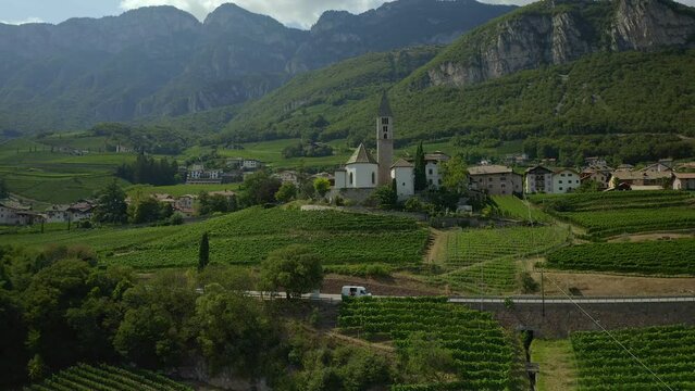Aerial drone view of Cortaccia village and iconic church on the Alps mountain landscape region in Italy