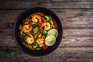 Shrimps, rice noodles, broccoli and shimeji mushrooms on wooden table 