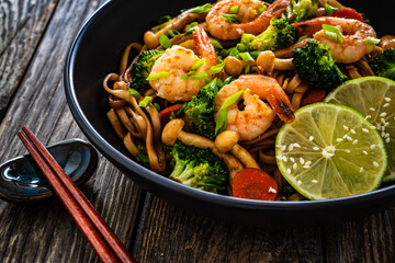 Shrimps, rice noodles, broccoli and shimeji mushrooms on wooden table 
