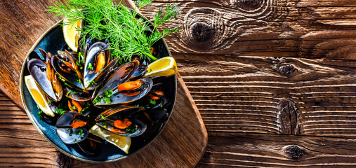 A plate of steamed mussels served with parsley and lemon