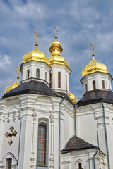 Fototapeta na wymiar Catherine's Church in Chernihiv, Ukraine, a resplendent white church adorned with golden domes, stands majestically against the canvas of a serene blue sky with drifting clouds.