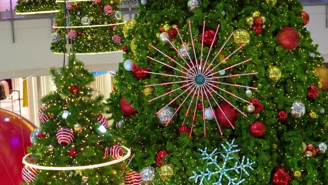 Texture background of branches of green decorated fragrant spruce toys, shiny balls, electric lights, garlands illumination. New Year Christmas mood background