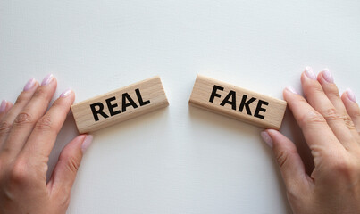 Real or Fake symbol. Concept word Real or Fake on wooden blocks. Businessman hand. Beautiful white...