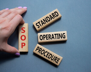 SOP - Standard Operating Procedure symbol. Wooden blocks with word SLA. Businessman hand. Beautiful...