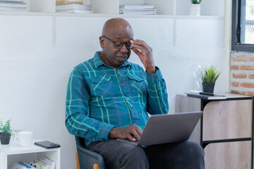 Portrait of happy African American small business owner. Millennial black smiling, sitting and using the laptop, and holding a cup of coffee work in modern office.