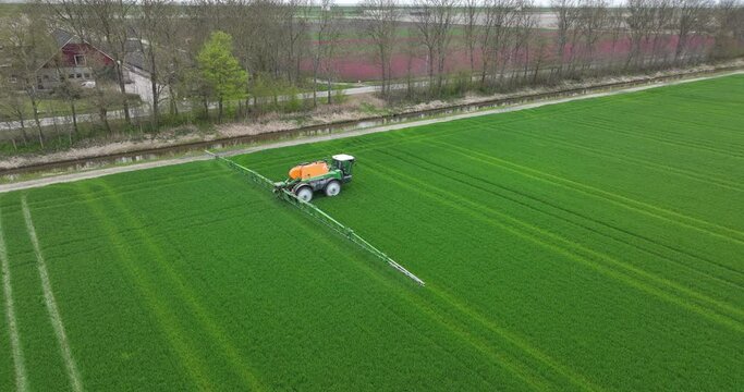 Creil, The Netherlands, 15th of April, 2023. Tractor in action: Aerial drone view of farmer applying pesticides to crops
