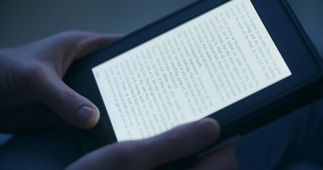 A woman reading an e-book in the evening or by night