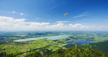 Hang glider flies above lake Forggensee in Bavaria, Germany - obrazy, fototapety, plakaty