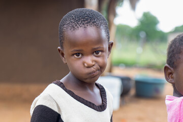 village african child, standing in the yard , playing pulling faces, skew mouth