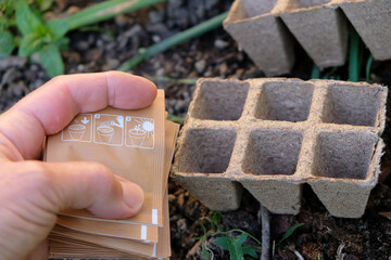 Paper bags with seeds in the gardener's hand. The empty peat pots. Cassette container for...