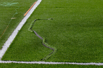 Closeup installation of football field with artificial turf with grass. Close up of line of an artificial football field. Details of artificial grass on stadium field. Football stadium with artificial