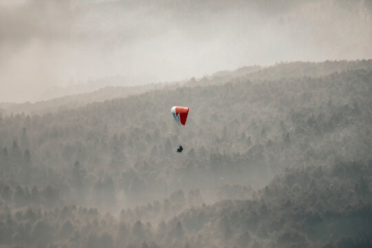 Paragliding concept, a paraglider pilot fly in the sky on the nature mountain landscape background.