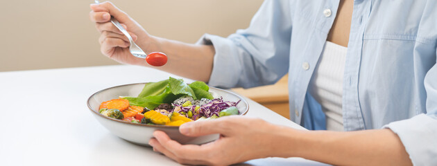Diet concept, close up young woman hand use fork to prick tomato, fresh vegetable, green salad in...