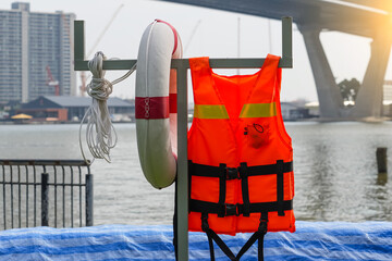 Life jacket and lifebuoy on a pole near the city river in the park.