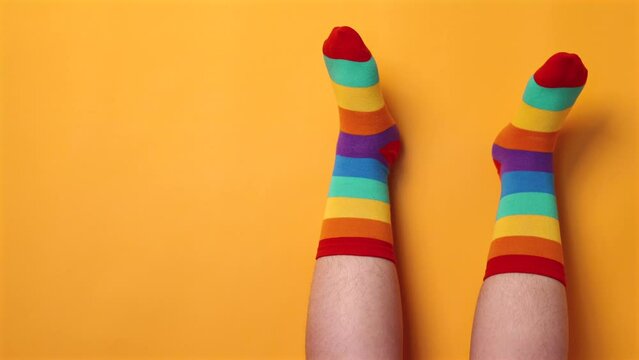playful feet on yellow background in rainbow color socks