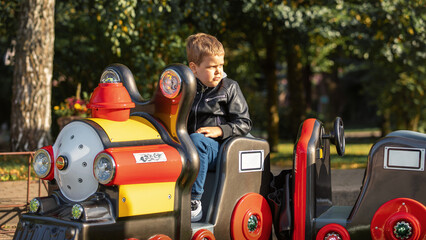 Mini colorful train for kids in a park in Palanga, Lithuania and a little boy in the train.