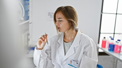 Captivating young woman, a blonde scientist deep in thought while staring at the computer in her...