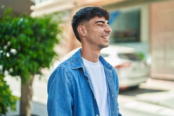 Young hispanic man smiling confident looking to the side at street