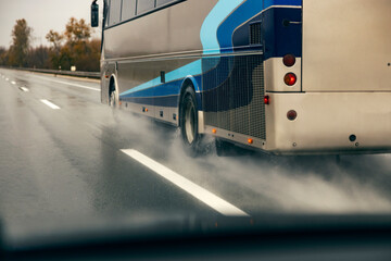 View from a vehicle of a bus driving on highway on rain.