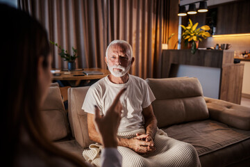 Portrait of a senior man listening to his doctor during her home visit.