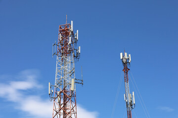 Mobile telecommunication towers on blue sky with white clouds. Cell tower with antennae and electronic communications equipment