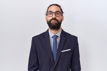 Hispanic man with beard wearing suit and tie relaxed with serious expression on face. simple and...
