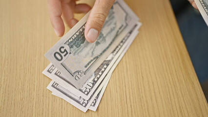 Hispanic man's hands busily counting dollars in professional office, a glimpse into the indoor...