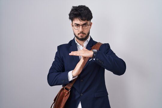 Hispanic man with beard wearing business clothes doing time out gesture with hands, frustrated and serious face