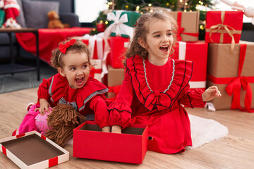 Fototapeta na wymiar Adorable girls celebrating christmas unpacking doll of gift at home