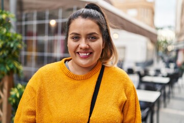 Young beautiful plus size woman smiling confident standing at coffee shop terrace