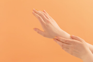 female hand with manicure on peach  background