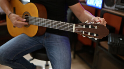 Obraz na płótnie Canvas Young hispanic man musician playing classical guitar at music studio