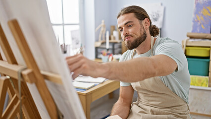 Young hispanic man artist drawing at art studio