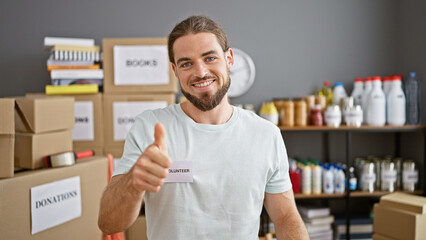 Young hispanic man volunteer smiling confident doing thumb up gesture at charity center