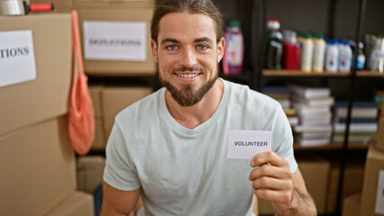 Young hispanic man holding volunteer paper smiling at charity center