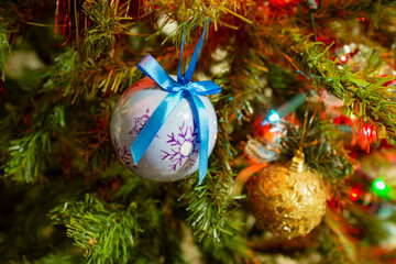 Festive christmas background. Multi-colored lights and balls on the branches of spruce. Blurry lights at night. Decorated Christmas tree on blurred background.